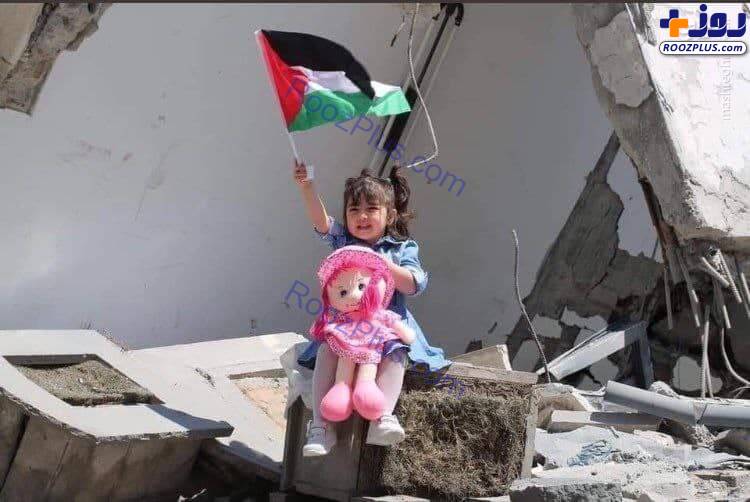 تصویری متاثر کننده از کودک غزه ای به همرا پرچم کشورش در میان خرابه‌ها